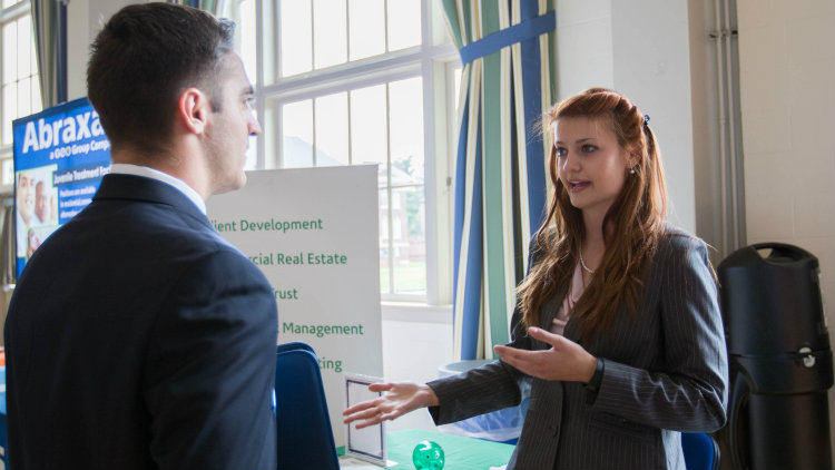 Rachel Fry interacts with a student at a job and internship fair.